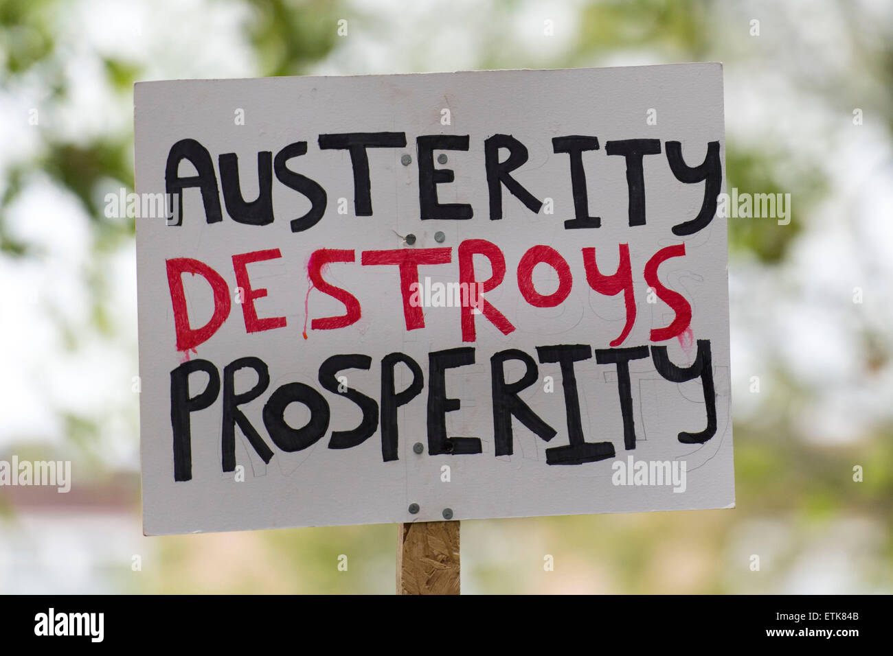 Eine gegen Sparpolitik zu unterzeichnen, dass liest "Sparmaßnahmen zerstört Wohlstand" bei einem Protest gegen die konservative Partei gesehen. Stockfoto