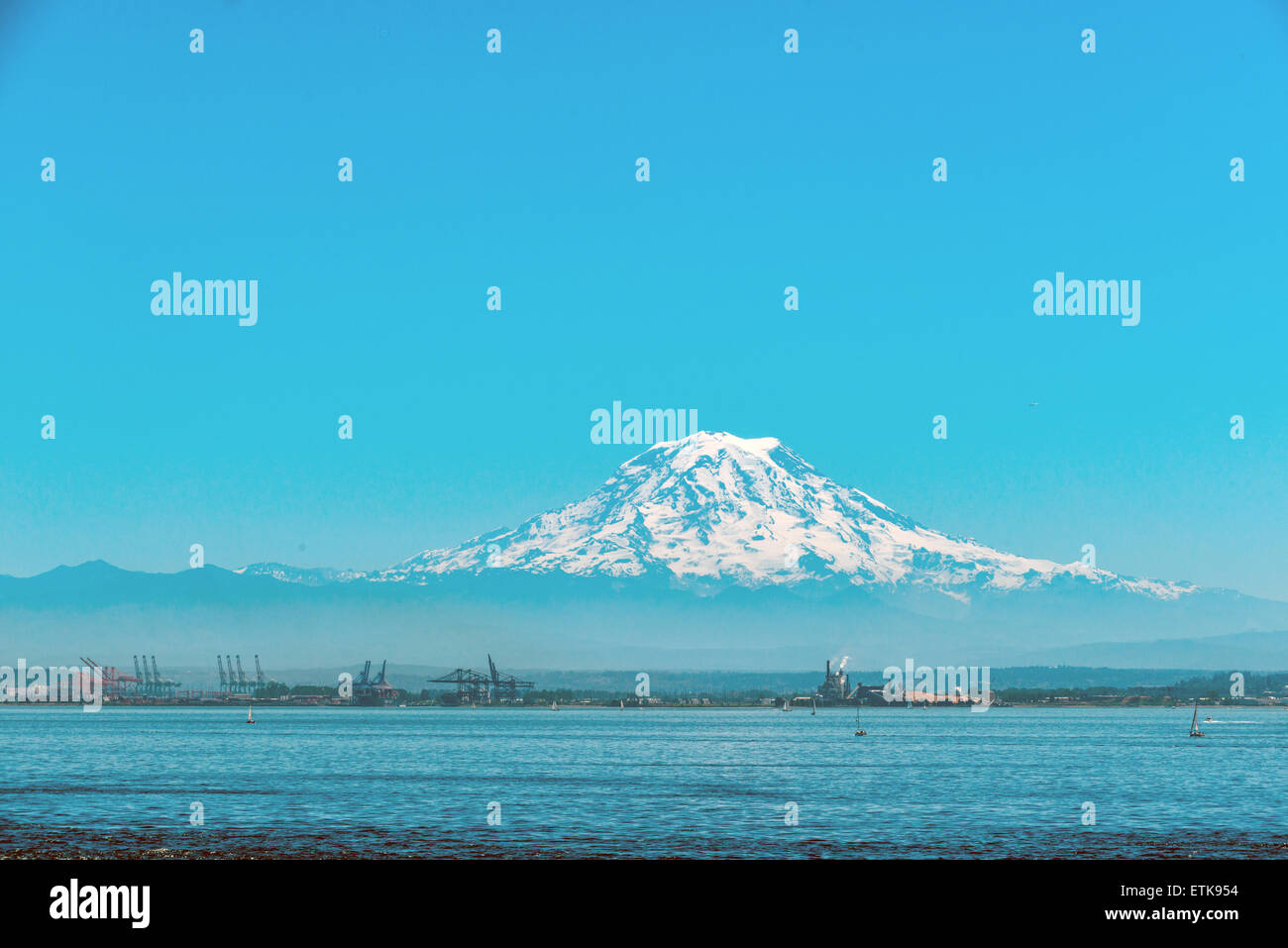 Mount Rainier erhebt sich über der Stadt und der Hafen von Tacoma aus dem Puget Sound in Washington State, USA. Stockfoto