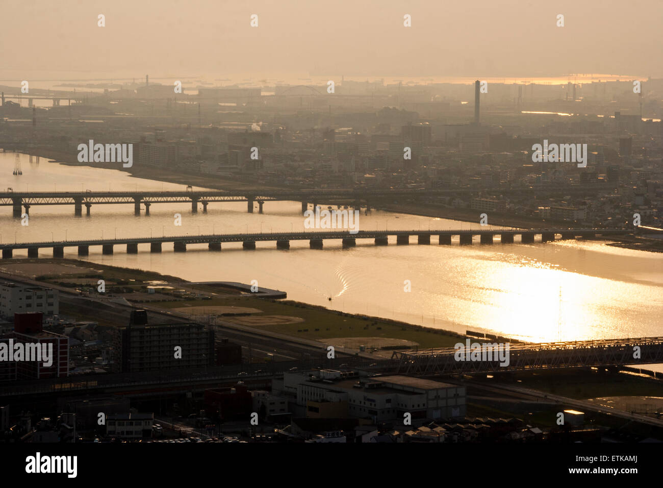 Luftbild vom Umeda Sky Building, Osaka, von Eisenbahn- und Straßenbrücken, die Kyu-Yodo, Yodo, Fluss, bei Sonnenuntergang, goldene Stunde überspannen. Hazy aufgrund von Umweltverschmutzung. Stockfoto