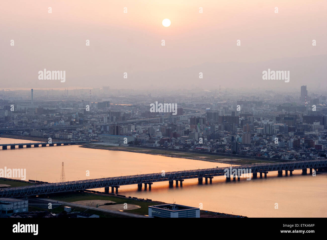 Luftbild vom Umeda Sky Building, Osaka, von Eisenbahn- und Straßenbrücken, die Kyu-Yodo, Yodo, Fluss, bei Sonnenuntergang, goldene Stunde überspannen. Hazy aufgrund von Umweltverschmutzung. Stockfoto