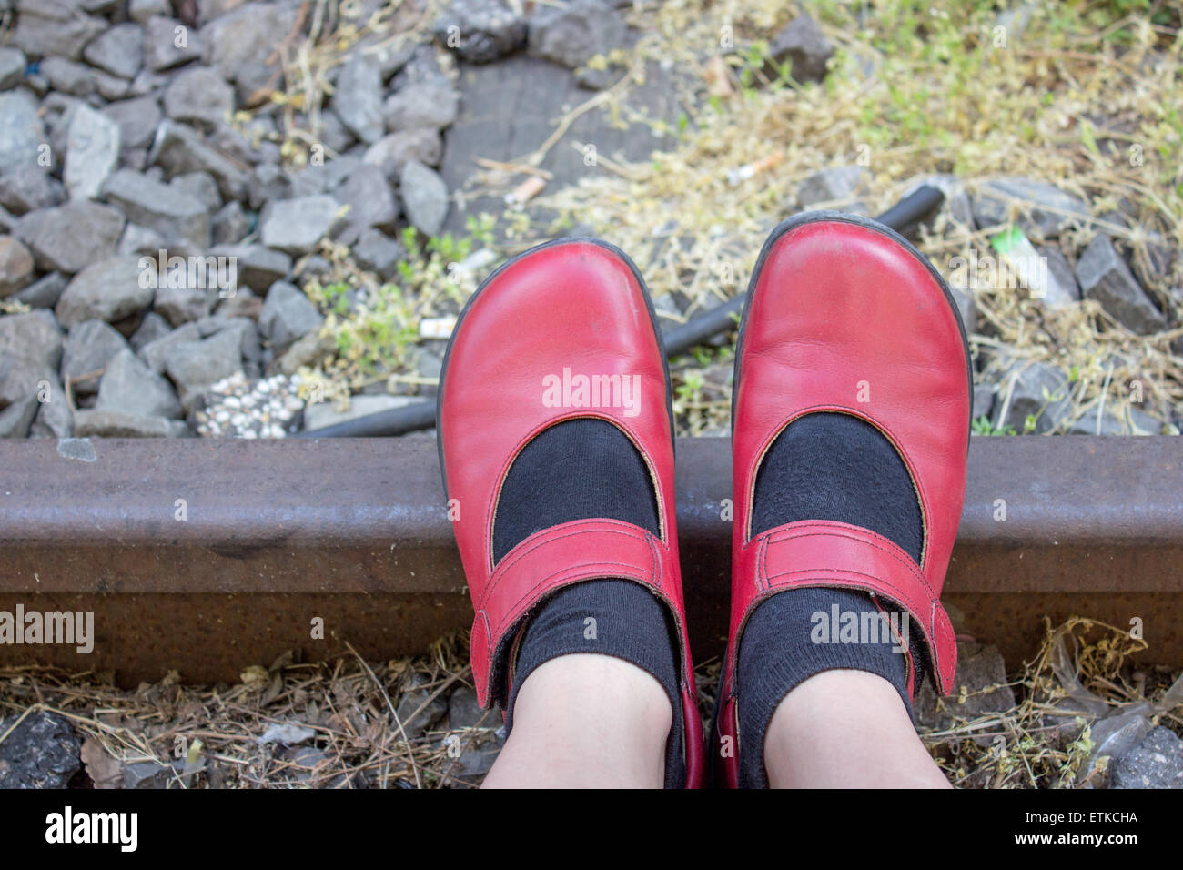 Füße mit roten Schuhen auf Schienen Stockfoto