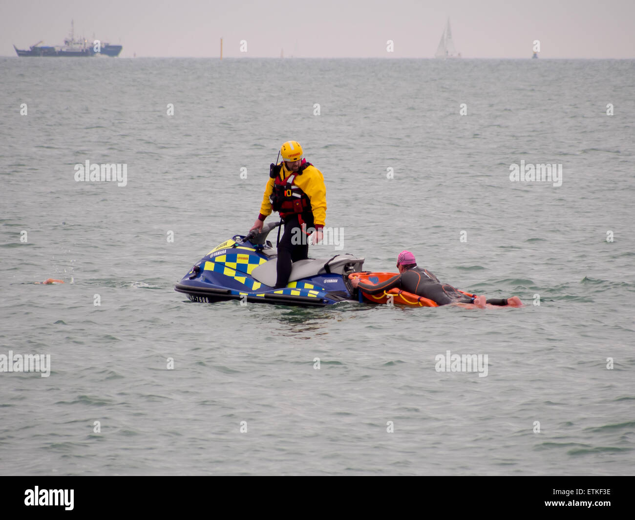Ein Rettungsschwimmer auf einem Jetski hilft einen Schwimmer, die in Schwierigkeiten stecken, während einer Triathlon-Veranstaltung im Solent Stockfoto
