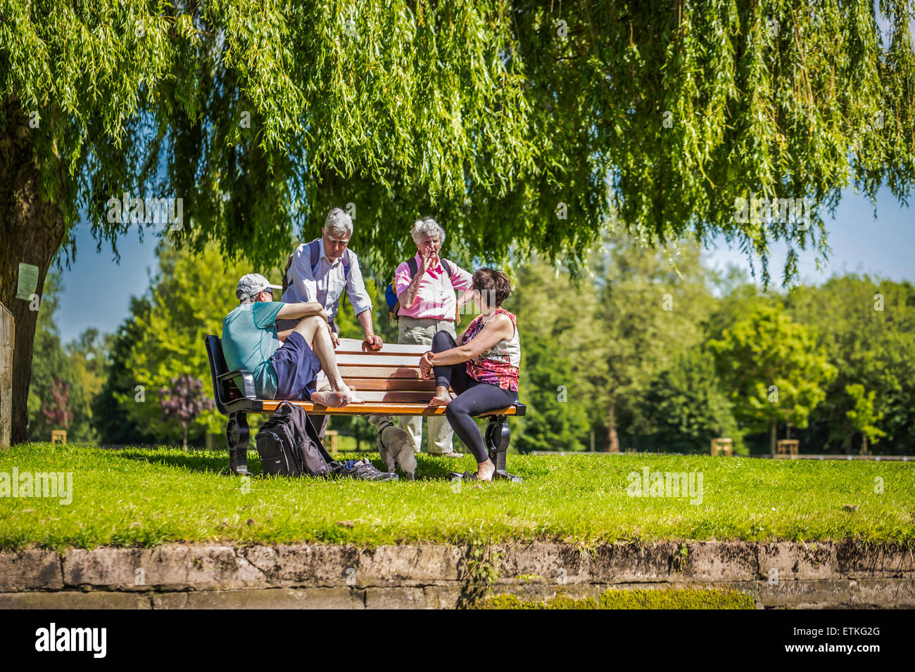 Zwei Paare besonders real in eine hitzige Diskussion auf einer Parkbank mit Blick auf den Fluss Avon. Stockfoto