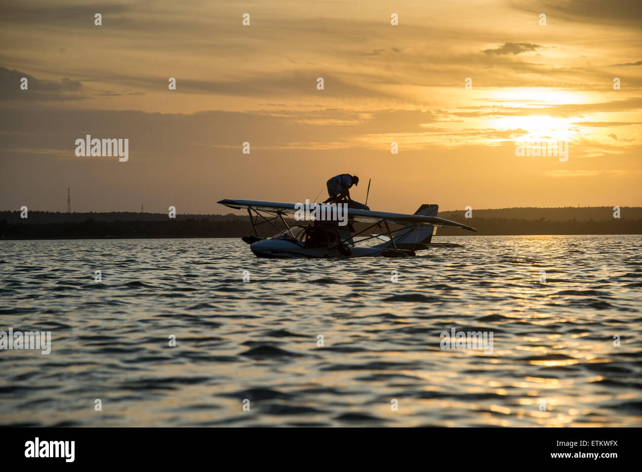 Man arbeitet an seinem Wasserflugzeug, umgeben von Wasser bei Sonnenuntergang in Südost-, USA Stockfoto