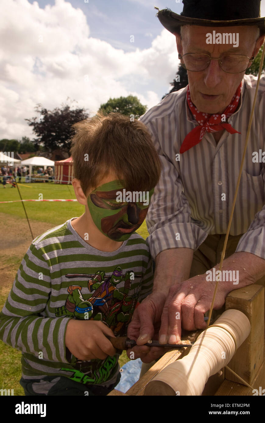 Handwerker, um jungen zu zeigen, das Handwerk der Herstellung aus Holz Kreiseln am Churt Fete, Churt, Farnham, Surrey, UK. Stockfoto