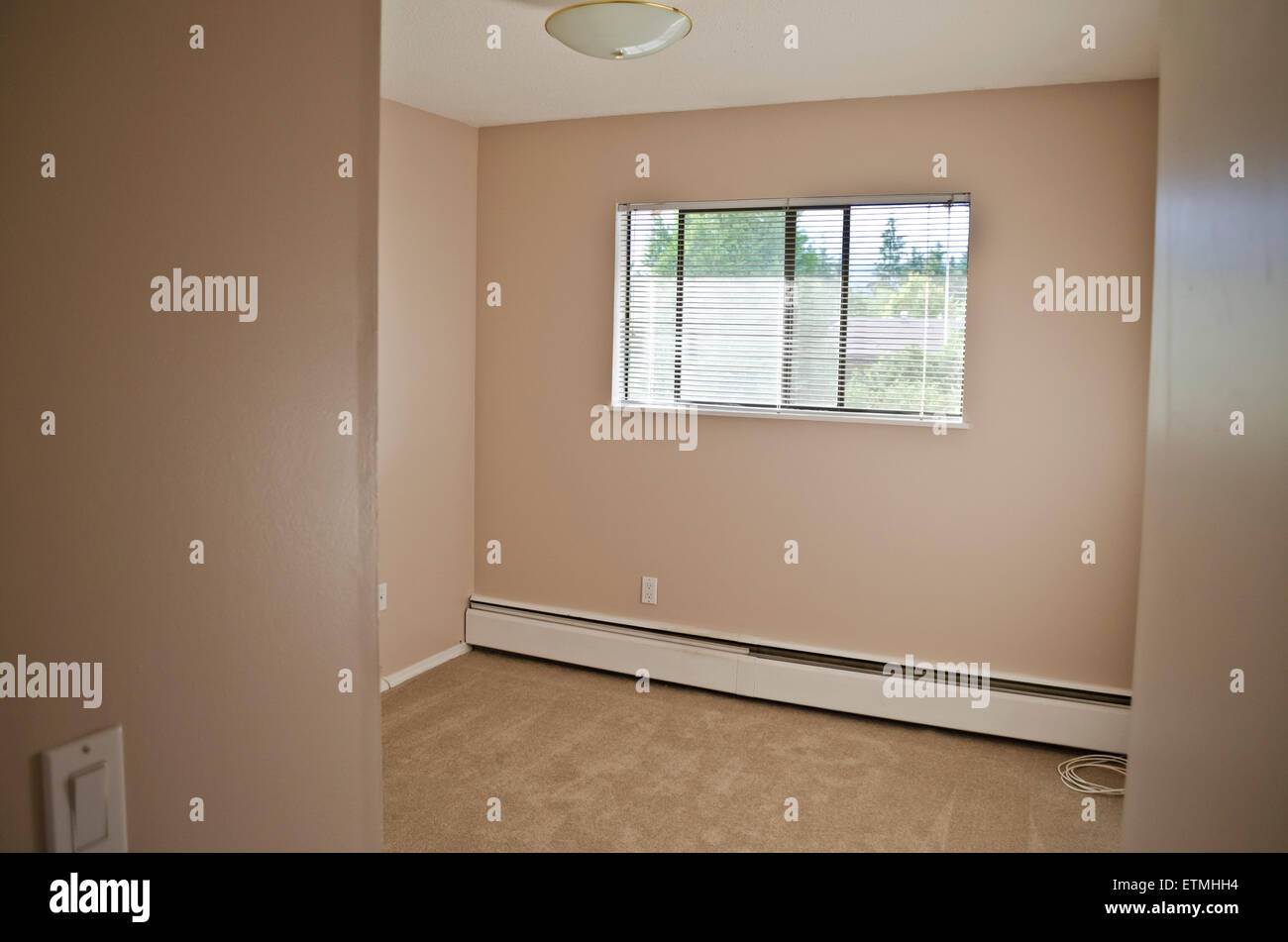 Kleine leere Schlafzimmer in einem Flachbau Wohnung in Greater Vancouver.  Beige Farbe an Wänden und Teppichboden. Stockfoto