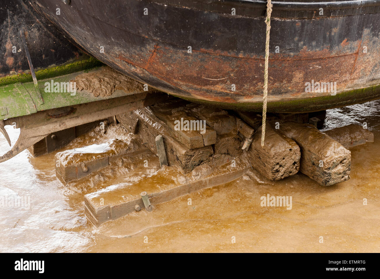 Alten Holzschwellen schützen die Basis von einem Flachboden Stahl Lastkahn auf Sandstraenden Restaurierung unterzogen Stockfoto