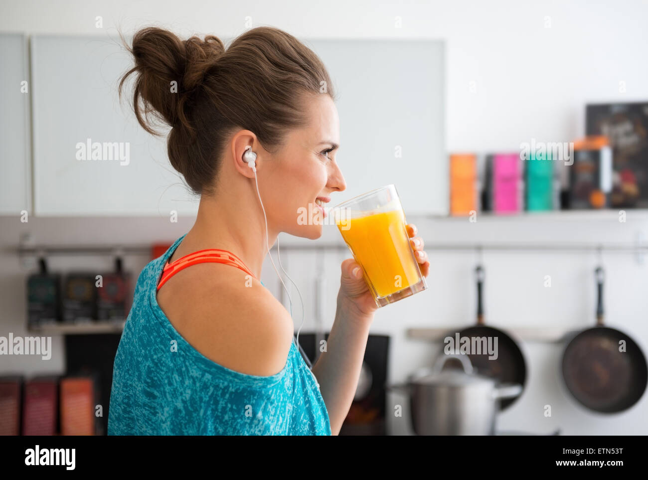 In ihrer modernen Küche steht eine Frau im Profil vor ihr frisch zubereiteten Smoothie zu trinken, mit Vitaminen vollgepackt ist. Eine gesunde Stockfoto