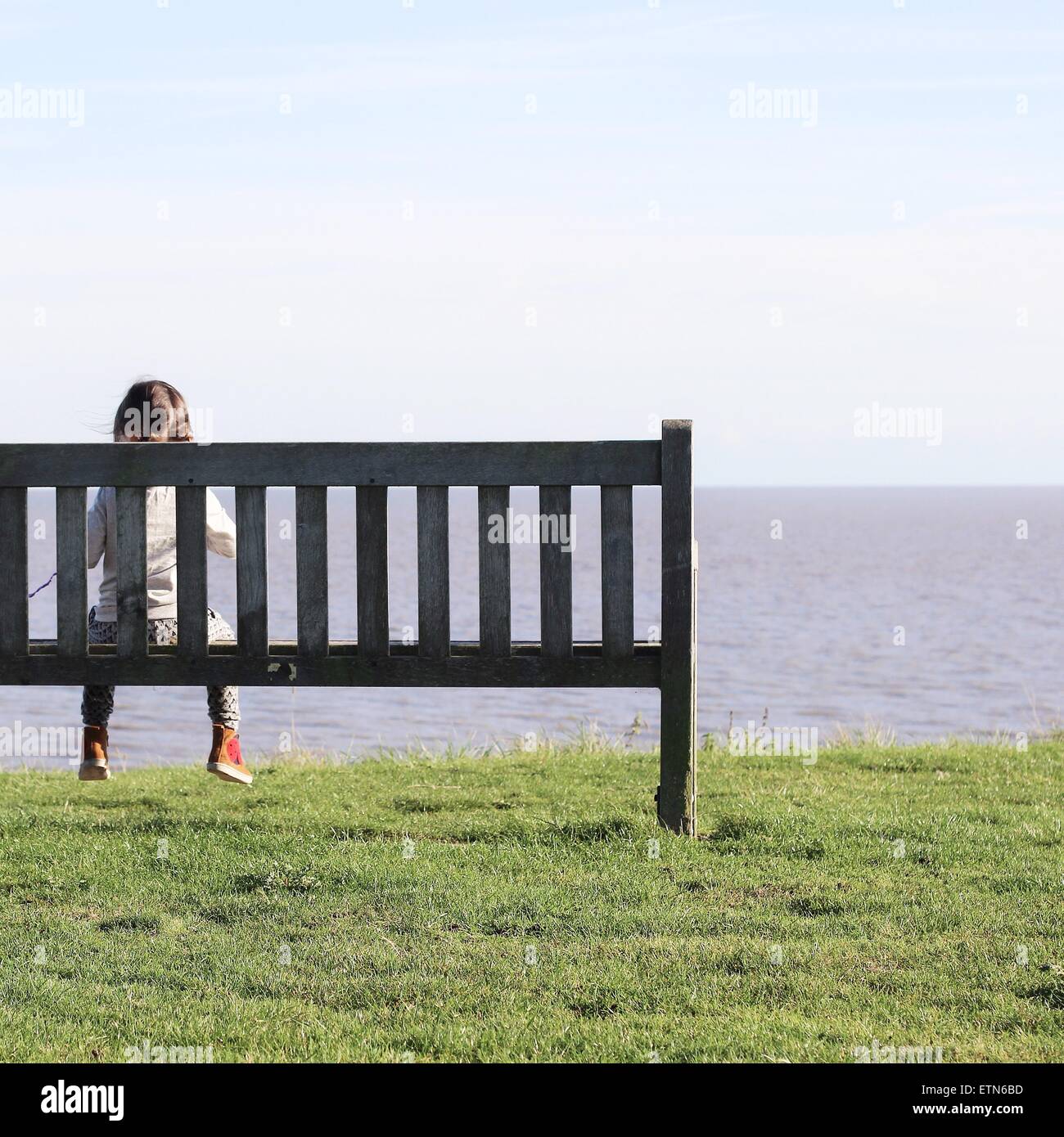 Mädchen sitzen auf Bank, Blick auf das Meer Stockfoto