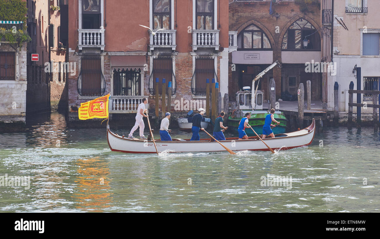 Ein Boot ruderte von sechs Männern und unter der venezianischen Flagge eines geflügelten Löwen bewegt sich entlang des Canal Grande Venedig Veneto Italien Europa Stockfoto