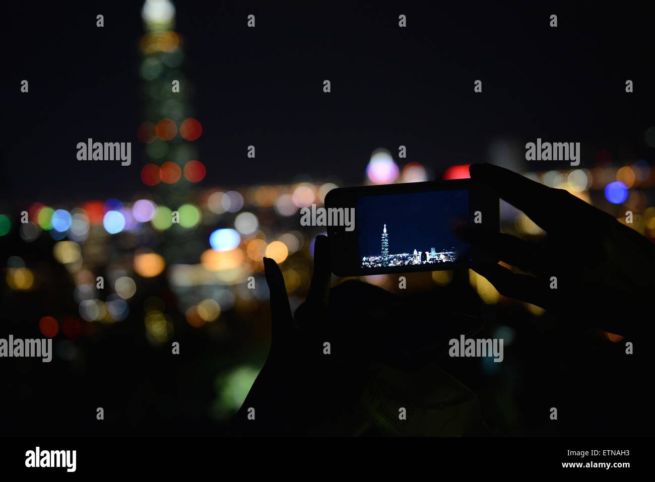 Silhouette einer Person, die ein Mobilgerät hält und ein Foto von Taipei, Taiwan, macht Stockfoto