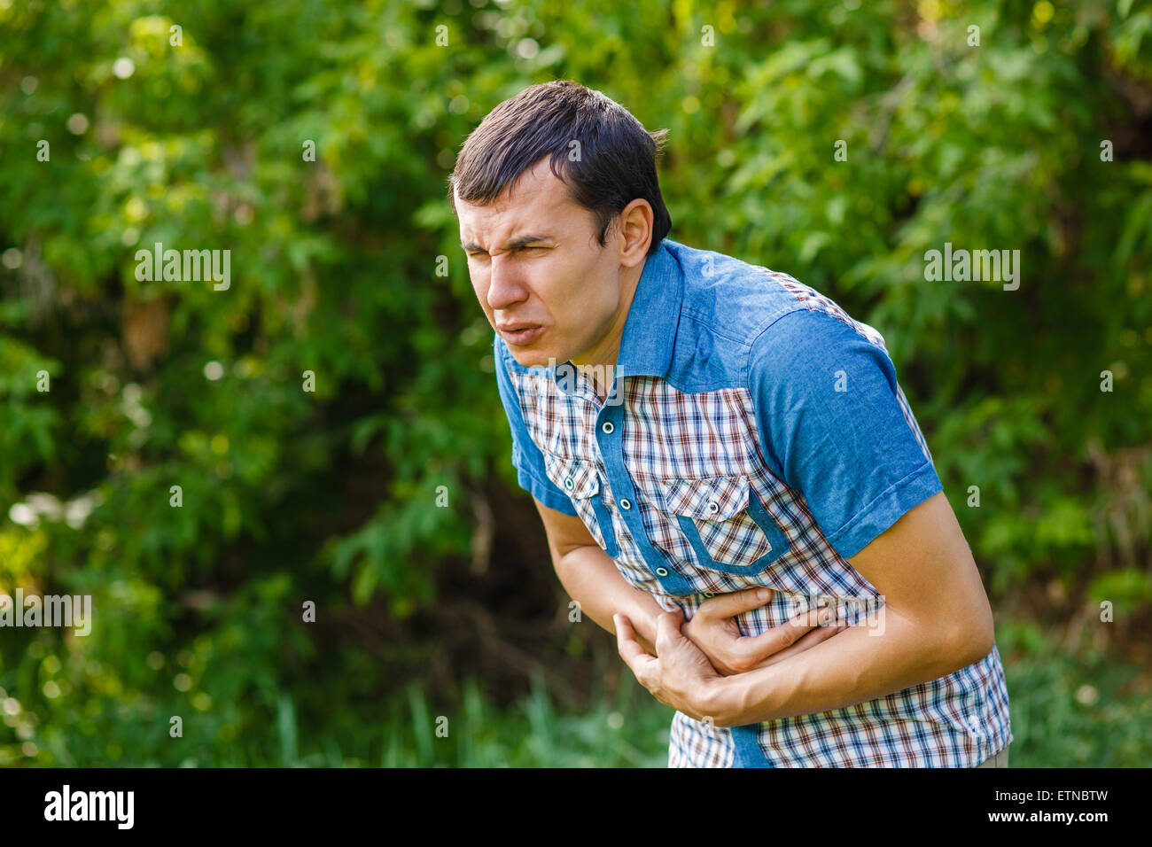 Mann auf der Straße Bauchschmerzen auf grünem Hintergrund lässt s Stockfoto