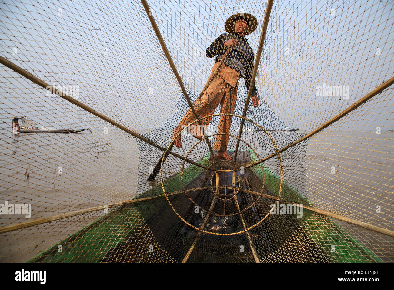 Ein traditionelles Fischer angeln in seinem Boot mit Netzen am Inle-See, Myanmar (Burma) Stockfoto