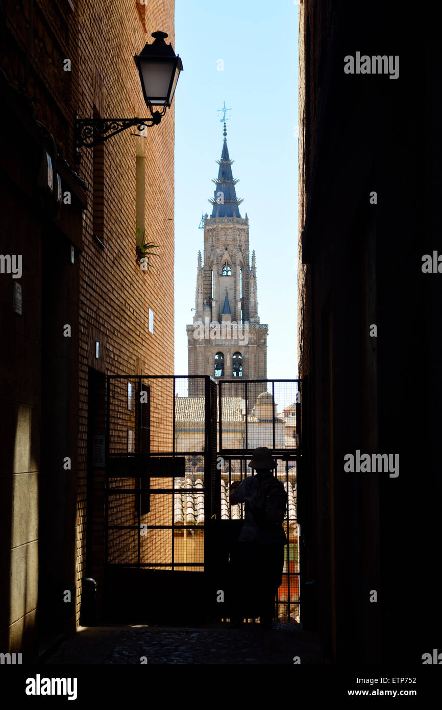 Silhouette der Person in der schmalen Gasse zwischen zwei Gebäude mit Turm der Kathedrale von Toledo über Stockfoto