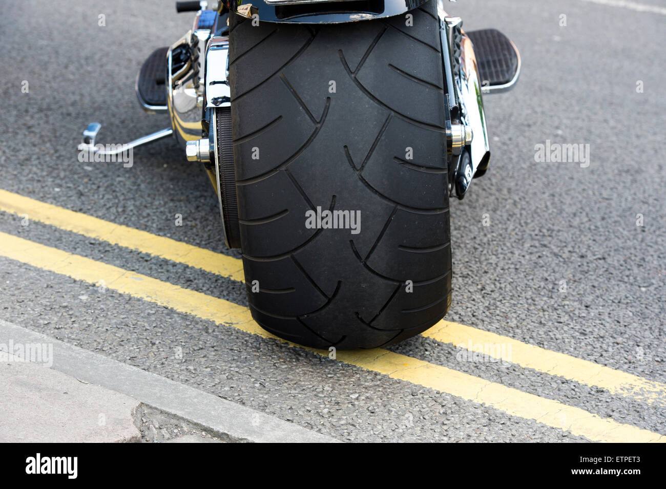Fett hinteren Reifen auf einer Harley Davidson Motorrad geparkt auf doppelte gelbe Linien Stockfoto