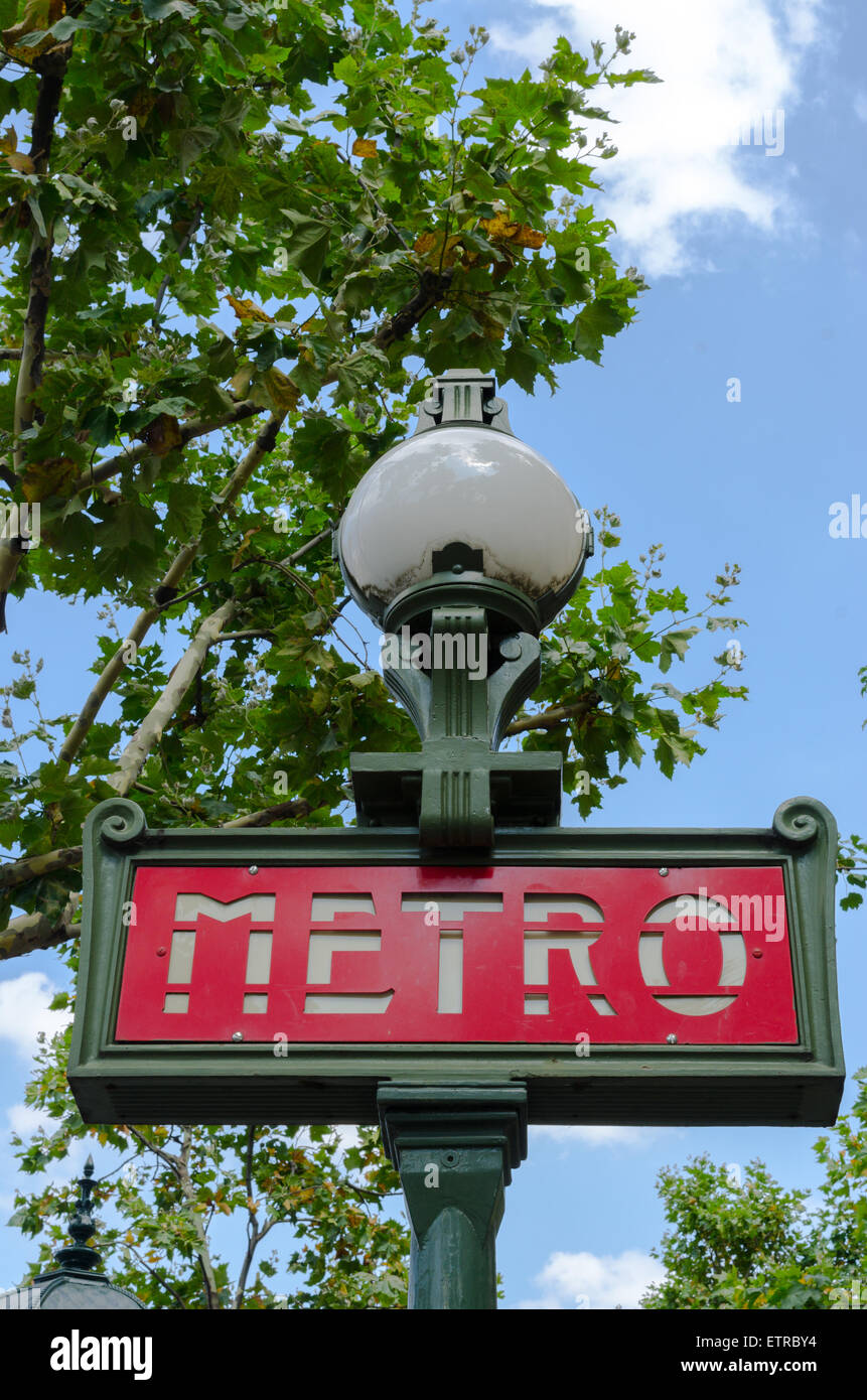 Traditionelle Paris Metro Schild um Bäume mit blauen Wolkenhimmel Stockfoto