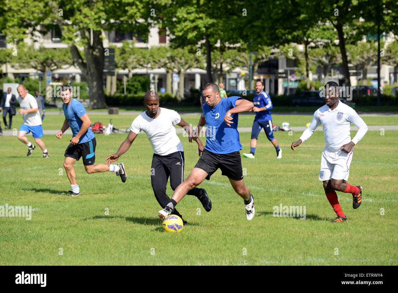 Amateurfußballspieler Männer jeden Alters spielen ein improvisiertes Spiel im öffentlichen Park von Annecy in Frankreich. Männer spielen Fußball im Park Stockfoto