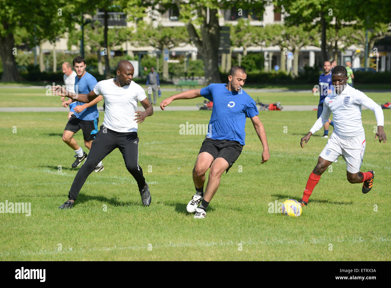Amateurfußballspieler Männer jeden Alters spielen ein improvisiertes Spiel im öffentlichen Park von Annecy in Frankreich. Männer spielen Fußball im Park Stockfoto