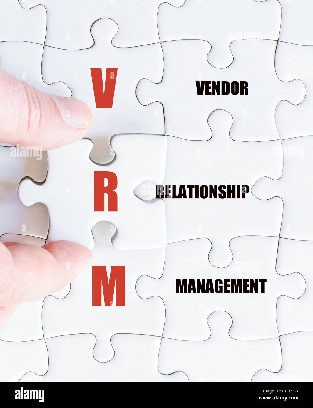 Hand eines Geschäftsmannes, die Vollendung des Puzzles mit das letzte fehlende Stück. Geschäft Akronym VRM als Vendor Relationship Management Stockfoto