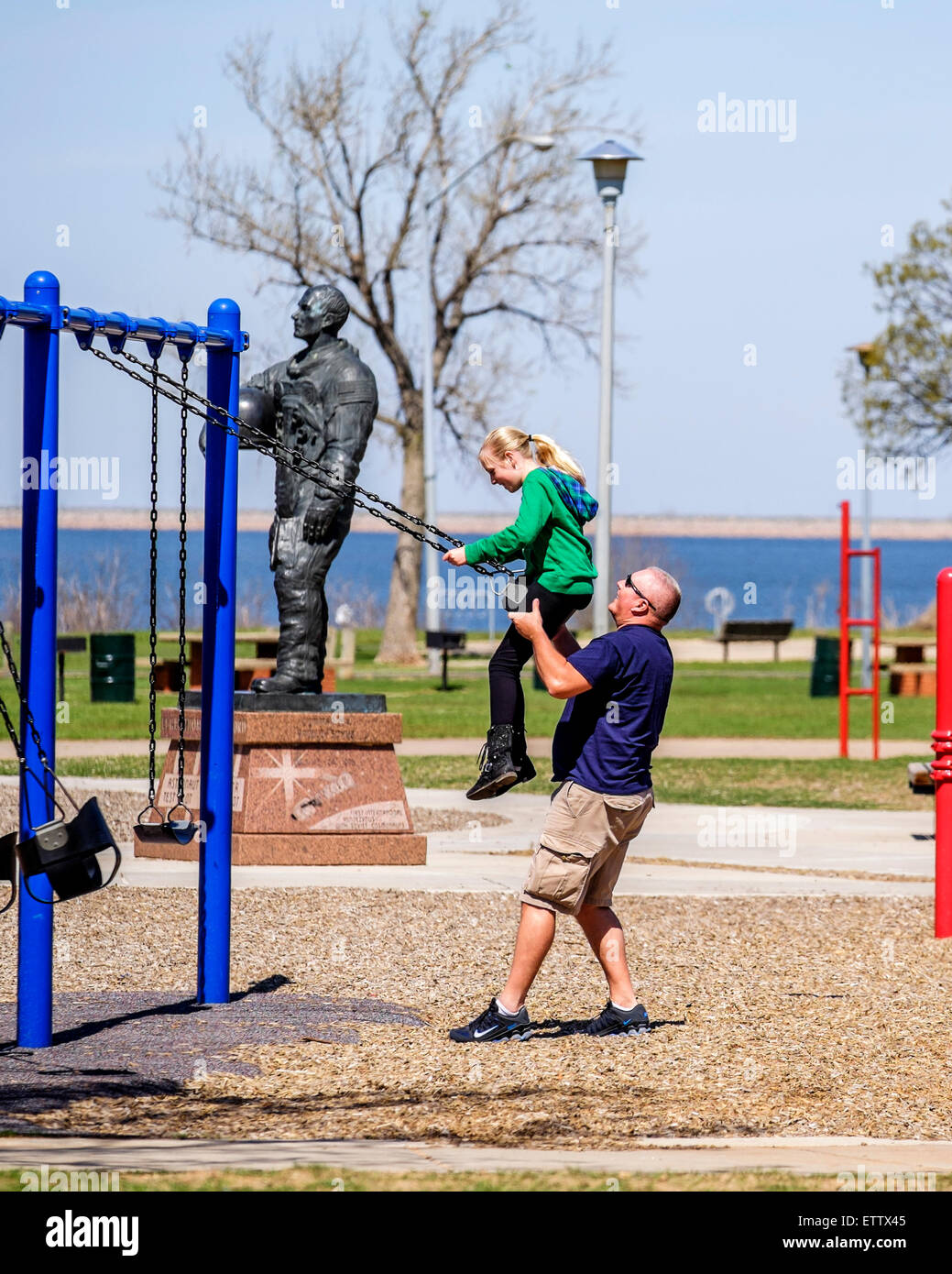 Kaukasische Vater schwingt seine Tochter im Stars And Stripes Park in Oklahoma City, Oklahoma, USA. Stockfoto