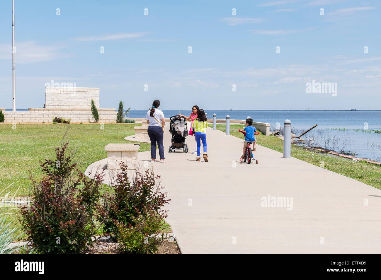 Eine spanische Mutter und Kinder gehen in Richtung der Eisenhower-Plaza am Lake Hefner, Oklahoma City, Oklahoma, USA. Stockfoto