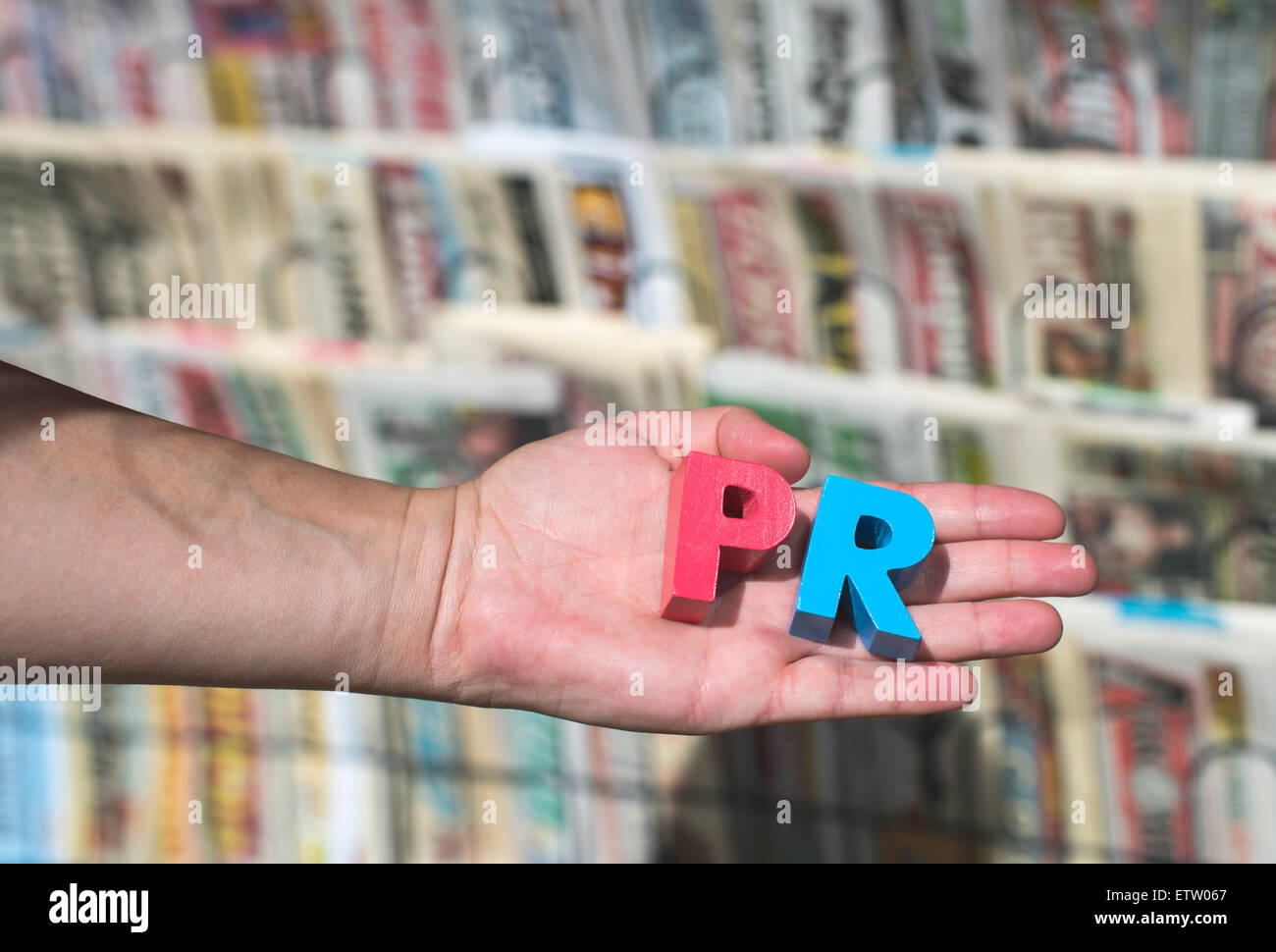 Wort-PR vor Kiosk für den Verkauf von Zeitungen und Zeitschriften, die Hände halten Holzbuchstaben Stockfoto