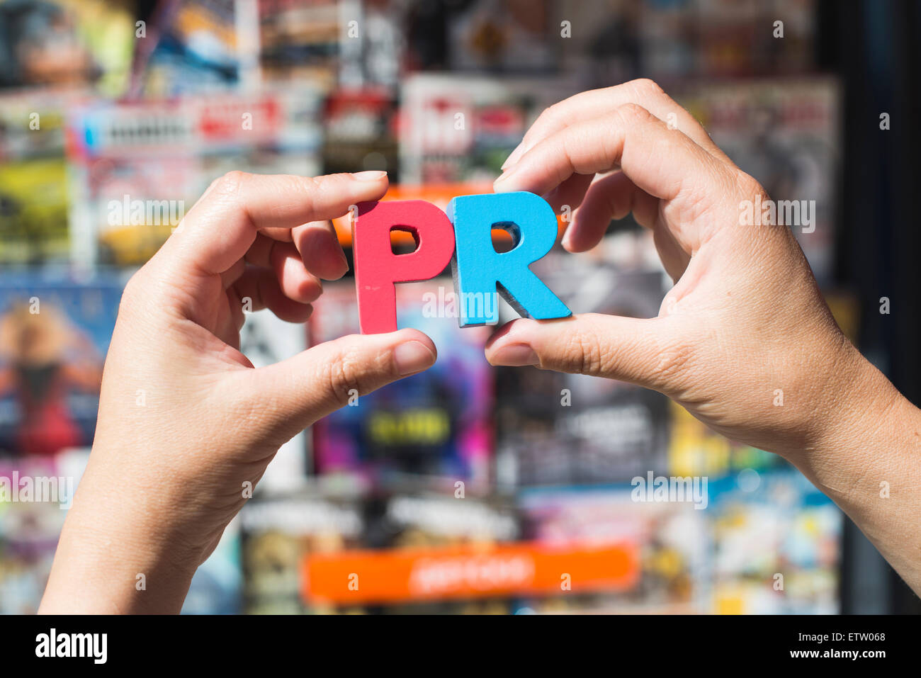 Wort-PR vor Kiosk für den Verkauf von Zeitungen und Zeitschriften, die Hände halten Holzbuchstaben Stockfoto