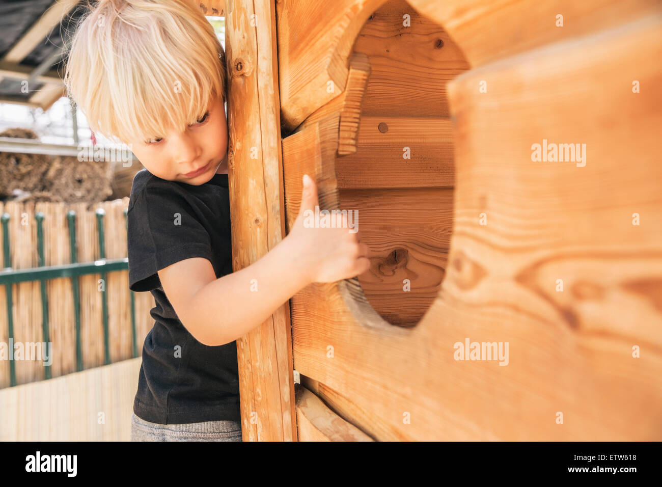 Kleiner Junge Blick in ein Loch der Holzschiff auf Spielplatz Stockfoto