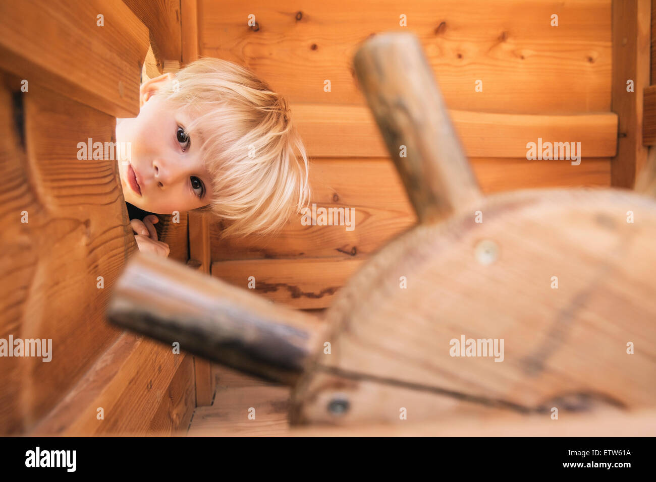 Kleiner Junge Blick durch Loch in Holzschiff auf Spielplatz Stockfoto