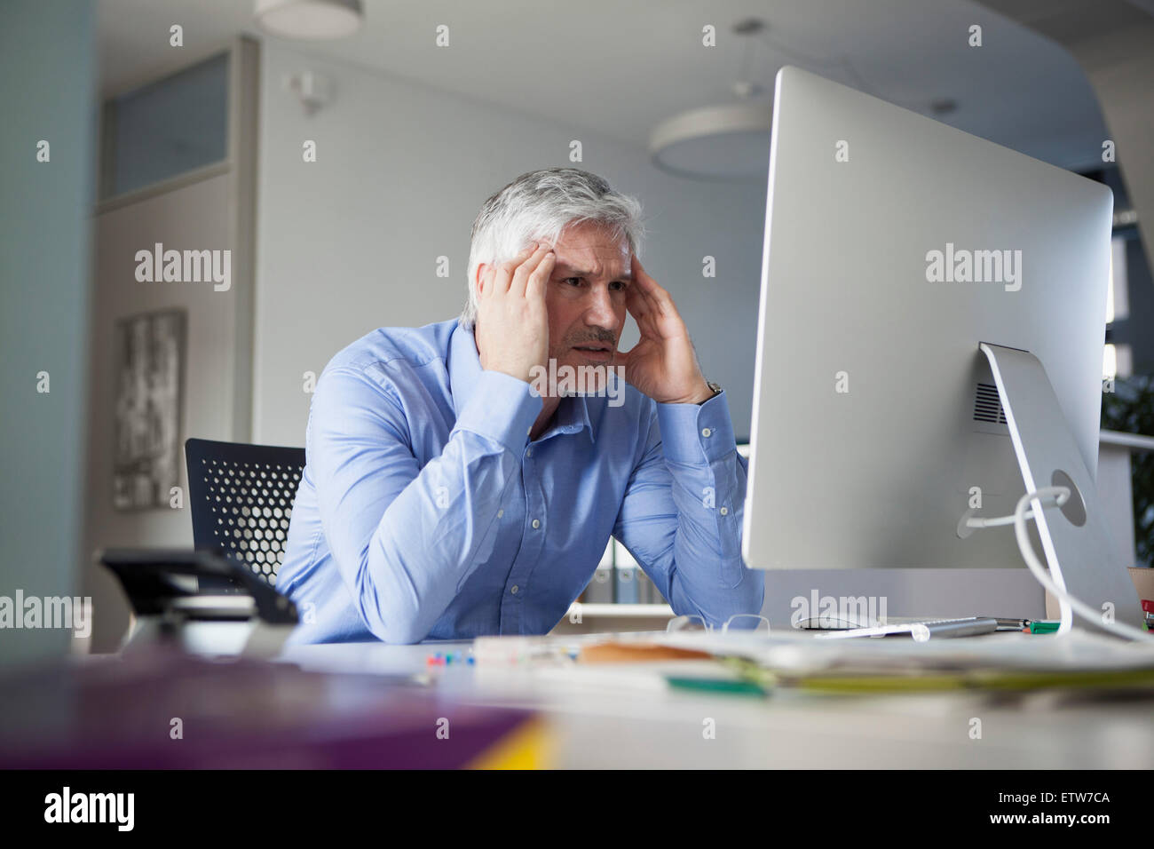 Geschäftsmann, sitzen am Schreibtisch, hand auf Kopf Stockfoto