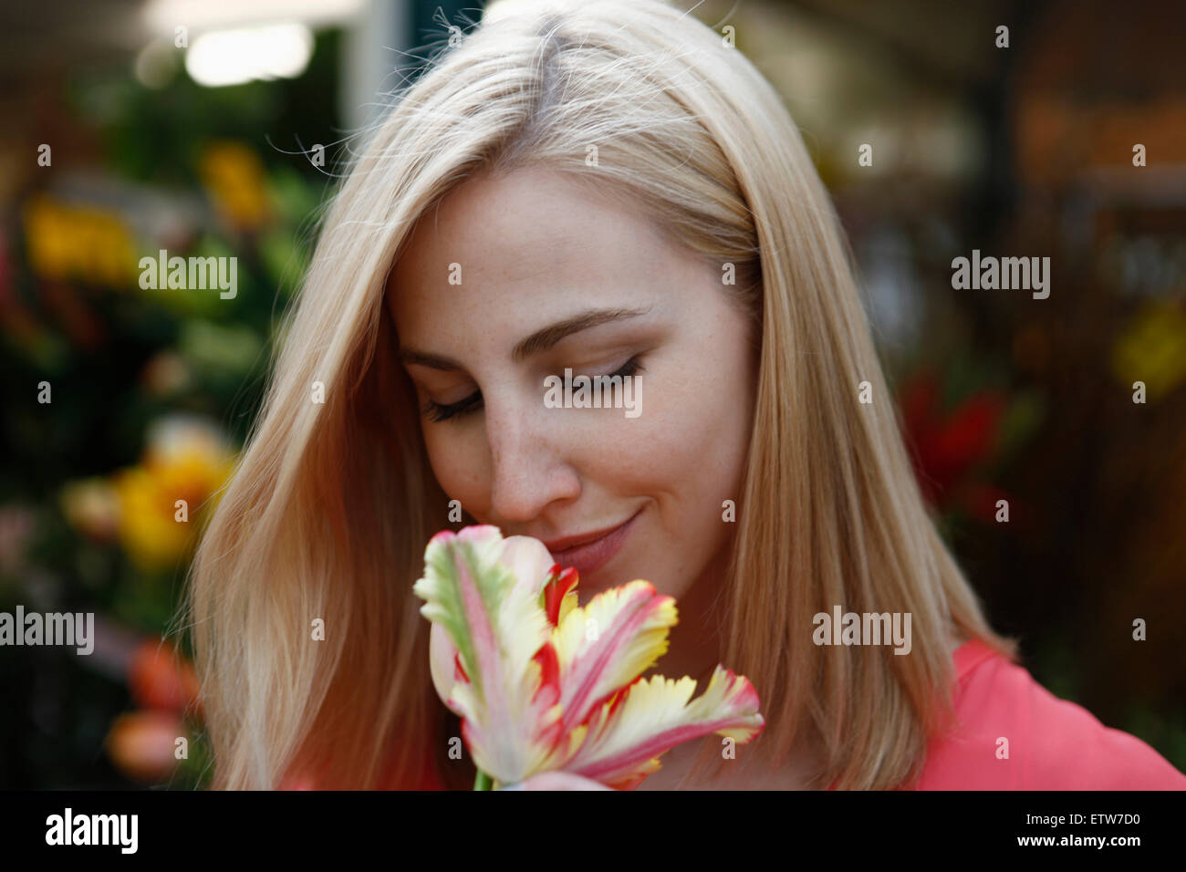 Blonde Frau riechende Blume auf Wochenmarkt Stockfoto