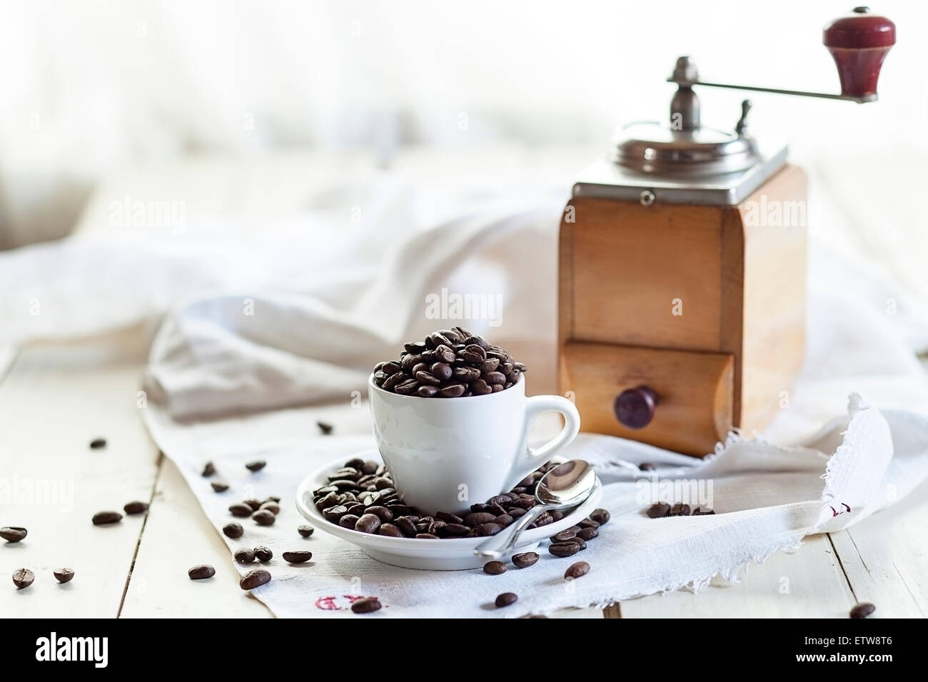 Alte Kaffeemühle und Kaffeetasse mit Kaffeebohnen gefüllt Stockfoto