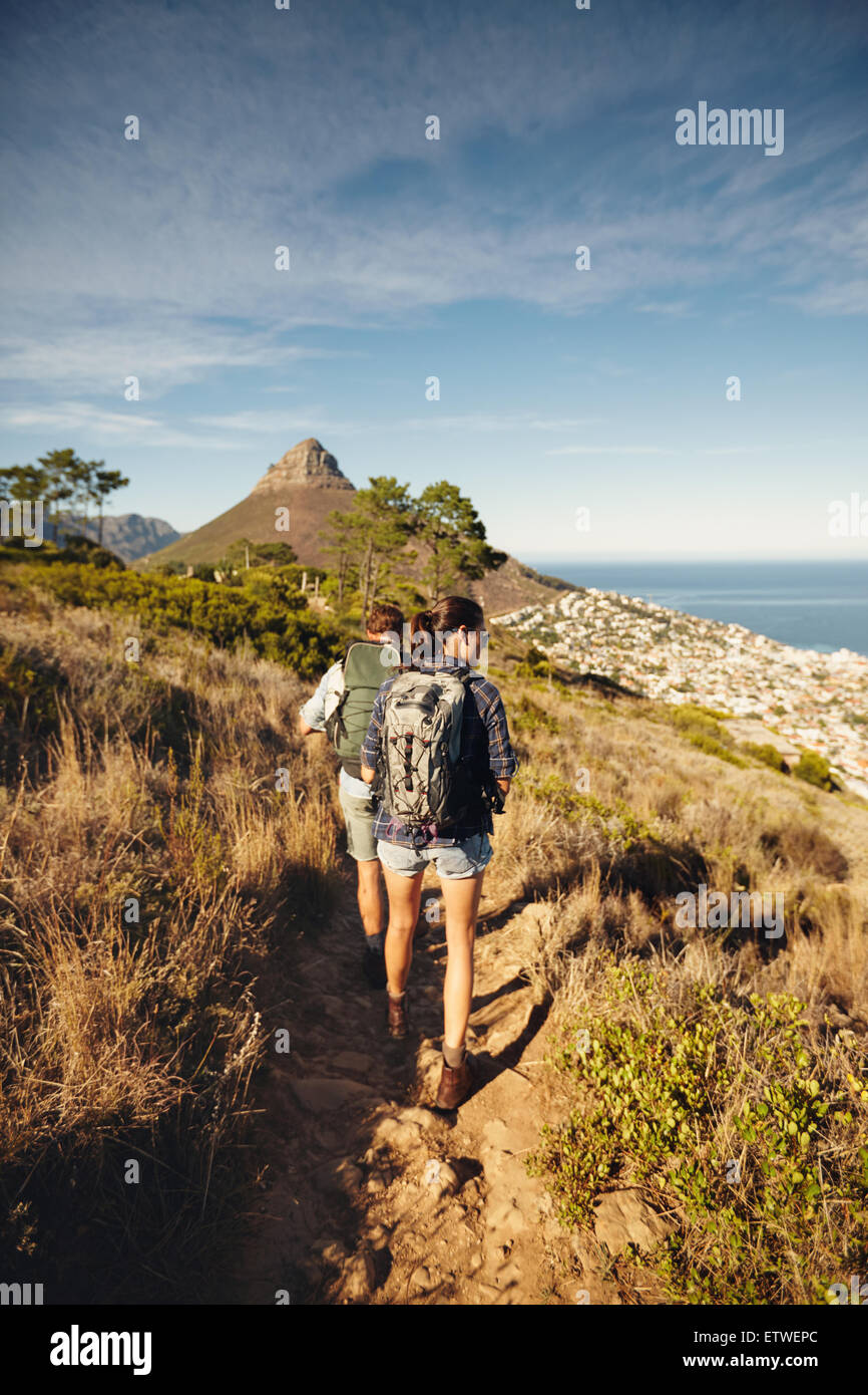 Rückansicht des Paares zu Fuß durch Feldweg am Berg. Junger Mann und Frau Wanderer Wandern in der Natur. Trekking zusammen summ Stockfoto