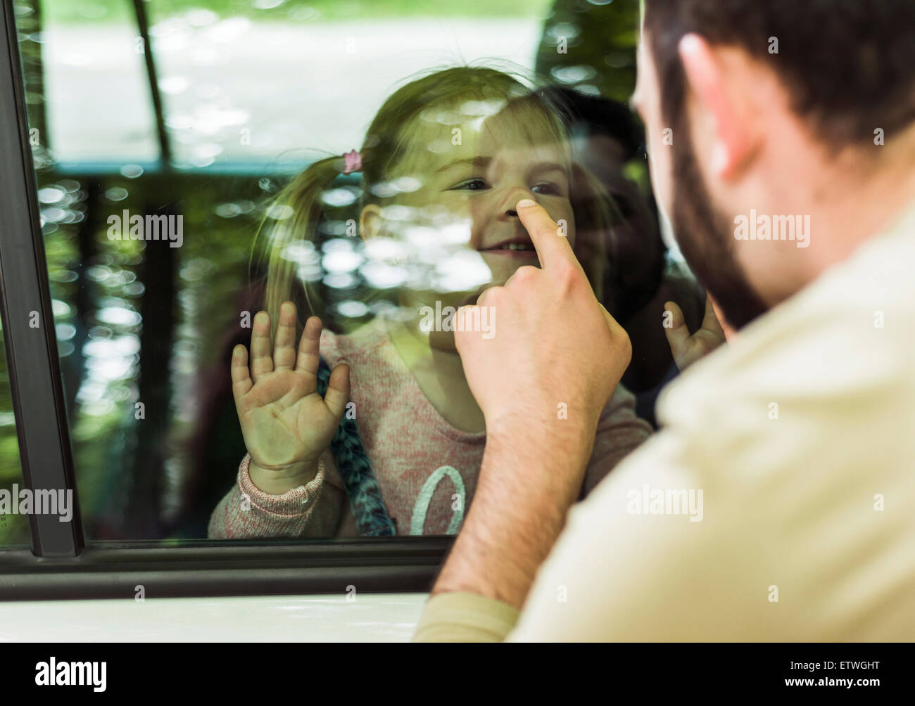Vater berühren Mädchens Nase hinter Autofenster Stockfoto