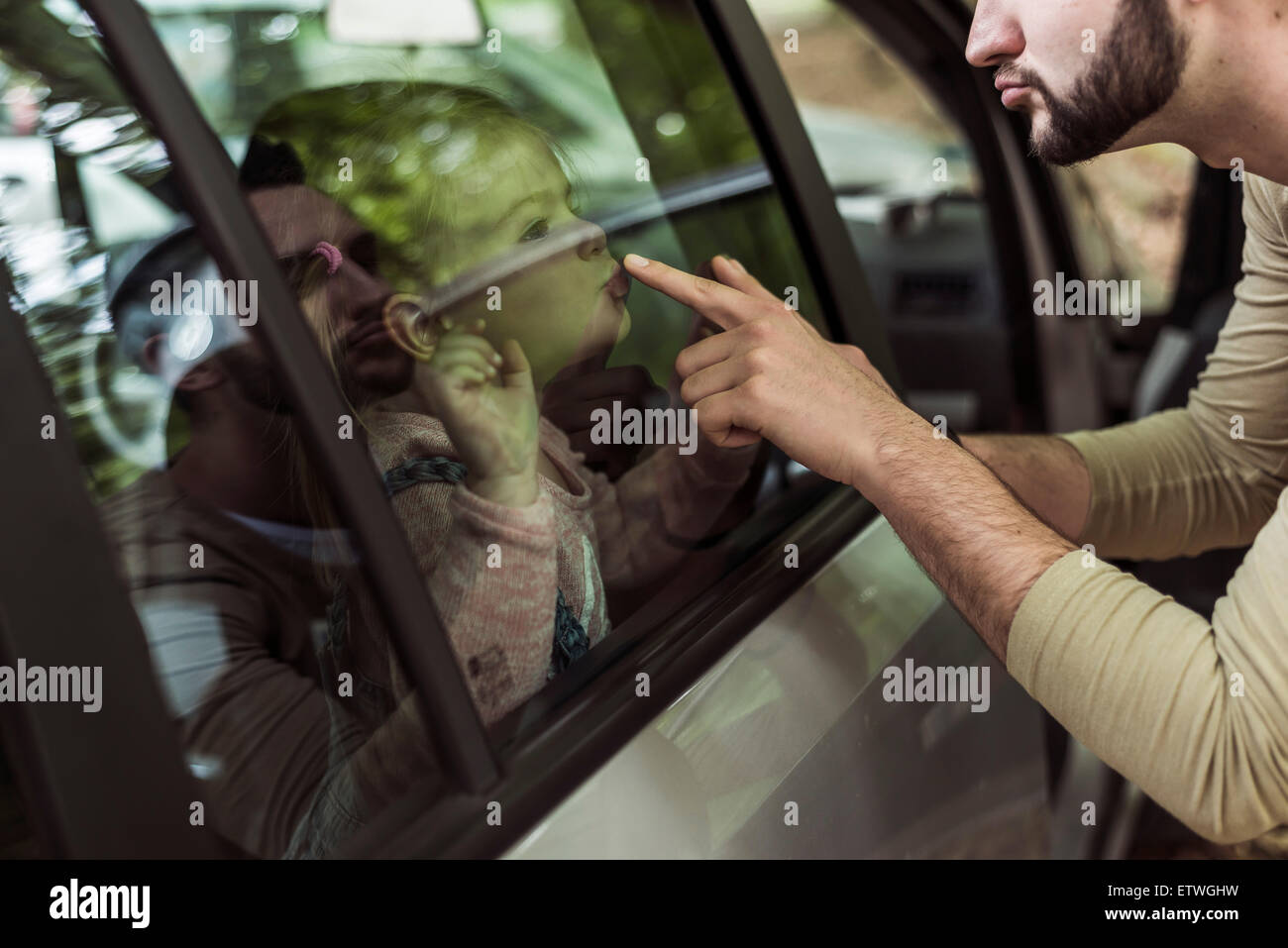 Vater rührende Mädchen Mund hinter Autofenster Stockfoto