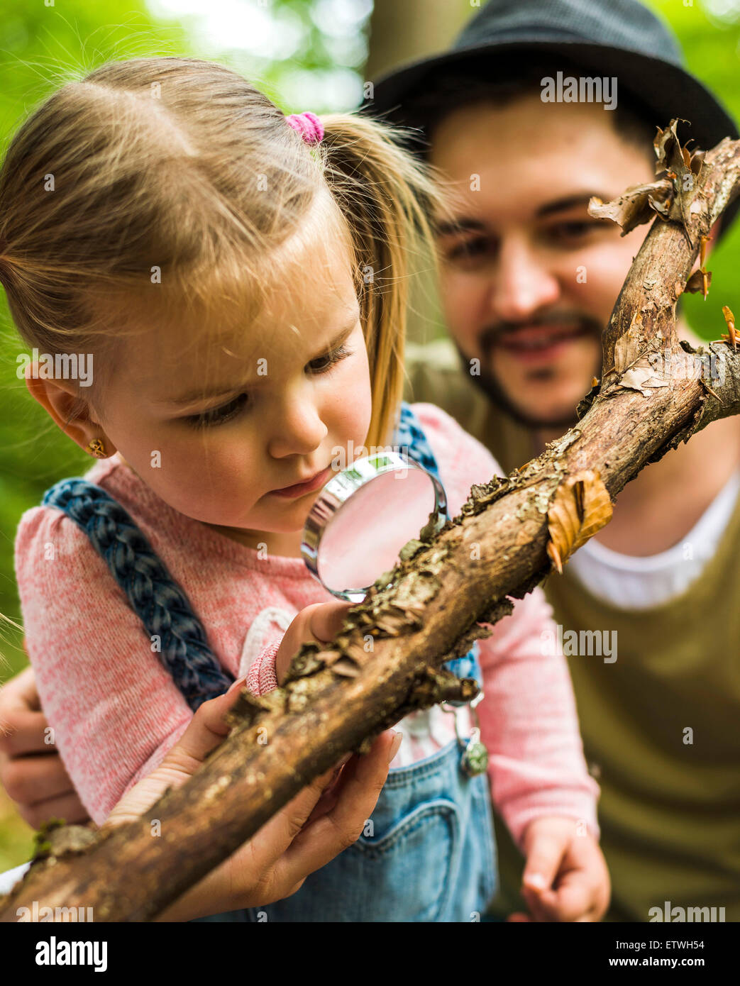 Mädchen mit Vater im Wald Prüfung Zweig mit Lupe Stockfoto