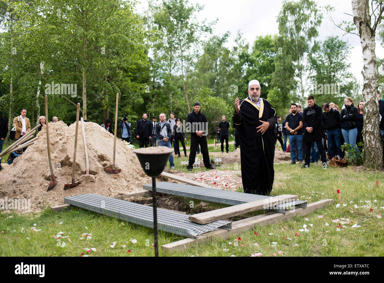 Imam Abdallah Hajjir (C) betet am Grab einer Frau aus Syrien, die im Mittelmeer in der muslimischen Abschnitt des Friedhofs in Berlin, Deutschland, Berlin-Gatow 16. Juni 2015 ertrunken. Die Beerdigung ist eine Aktion von "Zentrum für politische Schönheit" Aktivisten gegen die EU Flüchtlingspolitik protestieren organisiert. Die Frau Hinterbliebenen, die in Deutschland leben und vereinbart, die Aktion waren nicht anwesend. Im Gegensatz zu den Aktivisten Erklärung wird die Frau Kind, die auch im Flug ertrunken, nicht mit ihr begraben werden. Beide waren nach Angaben der Aktivisten an Bord eines Schiffes Stockfoto