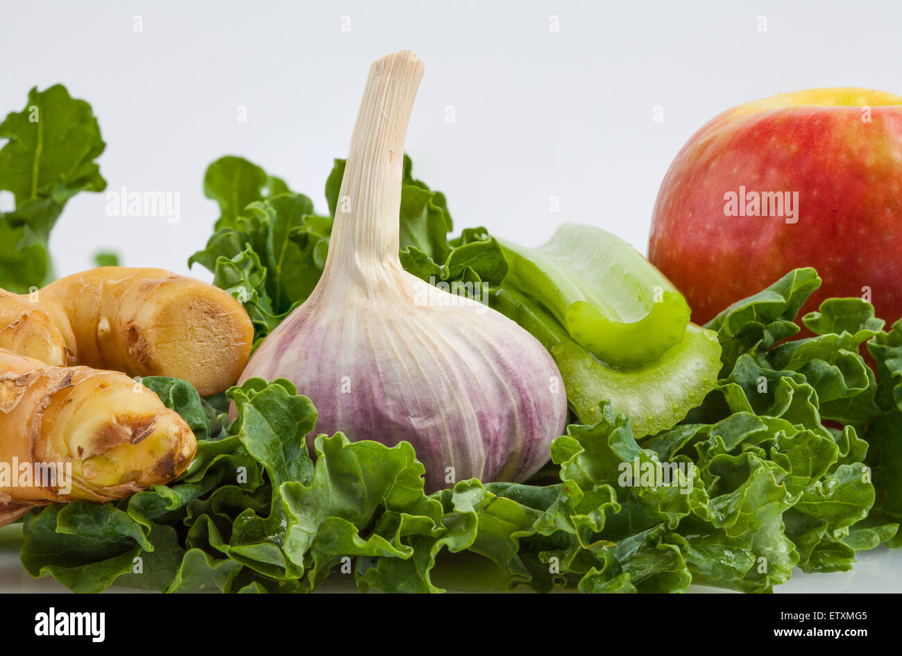 Zutaten für Grünkohl shake auf weißem Hintergrund extreme Nahaufnahme - Ingwer, Knoblauch, Grünkohl, Pink Lady Apfel, Sellerie Stockfoto