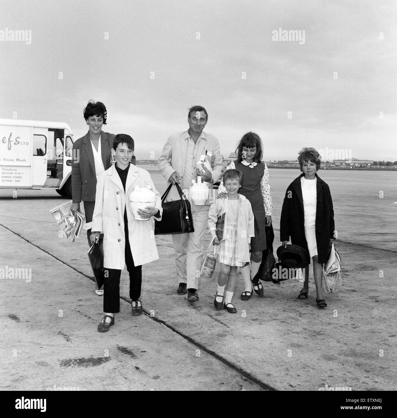 Spike Milligan und Familie zurück von einem dreiwöchigen Urlaub in Marbella, Flughafen London abgebildet. Abgebildet sind, Spike mit seiner Frau Paddy und Kinder aus früherer Ehe Spike, Sean (10), Sile (7) und Laura (12), auch mit ihnen ist die Kinder-nan Stockfoto