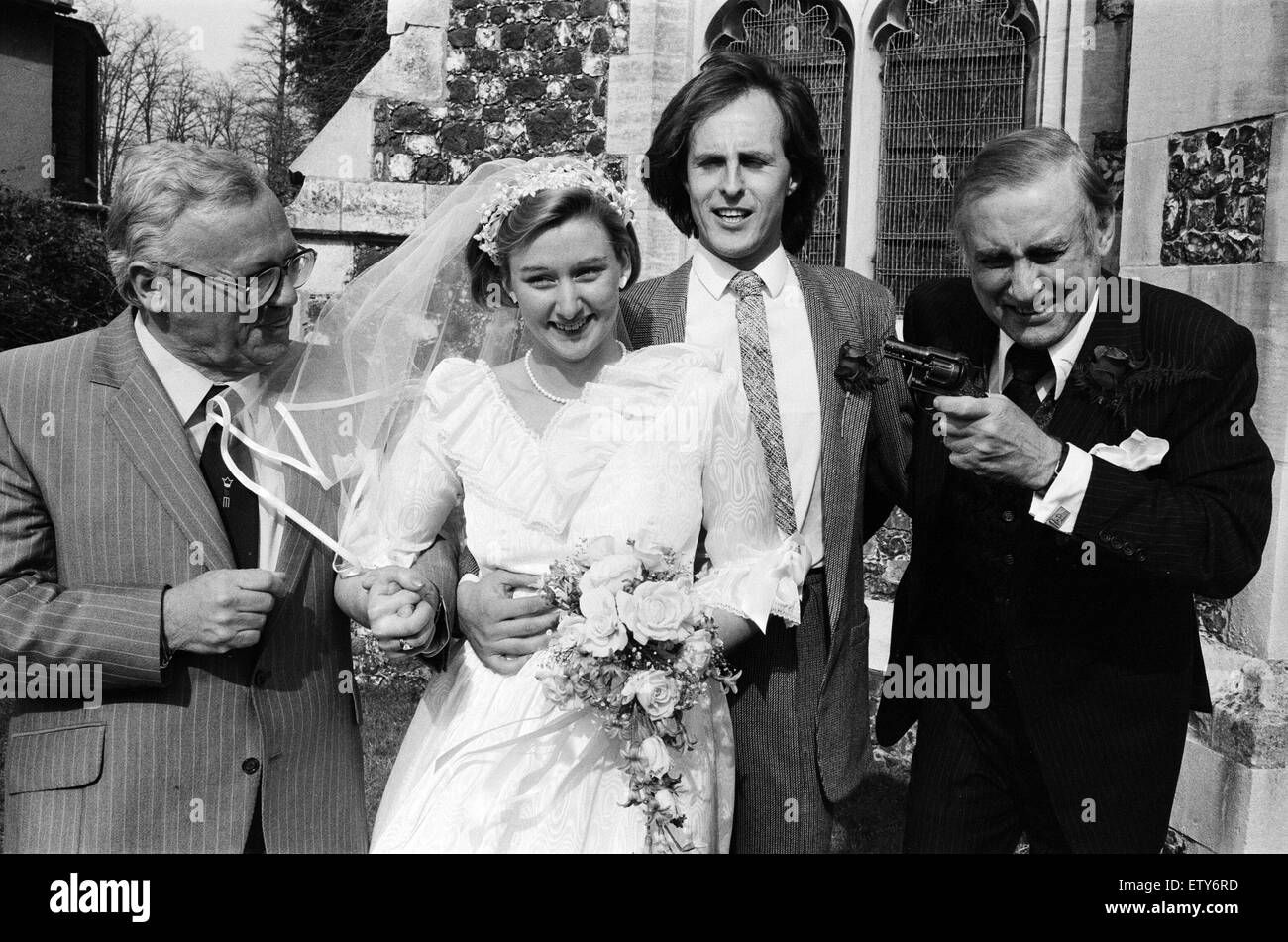 Die Hochzeit von Spike Milligan Tochter Sile, Willie White. Spike Milligan mit einem Scherz mit einer Spielzeug-Pistole, auch abgebildet ist Harry Secombe. Kirche der Jungfrau Maria, Monken Hadley, Barnet, London. 14. April 1984. Stockfoto
