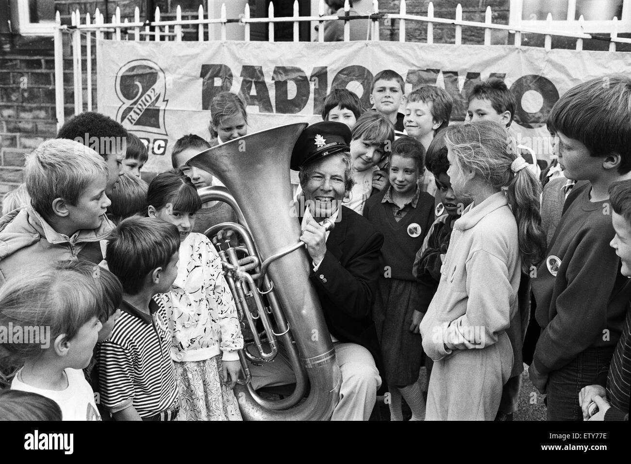 COR Blimey - es ist Derek Jameson... Derek, komplett mit Cockney Akzent und ansteckenden Lachen diese Kinder an Hinchliffe Mill Junior und Säuglinge School, Holmbridge, begeistert von Radio 2-Sterne Versuche Tuba spielen heute Morgen. Als Reaktion auf ein lette Stockfoto