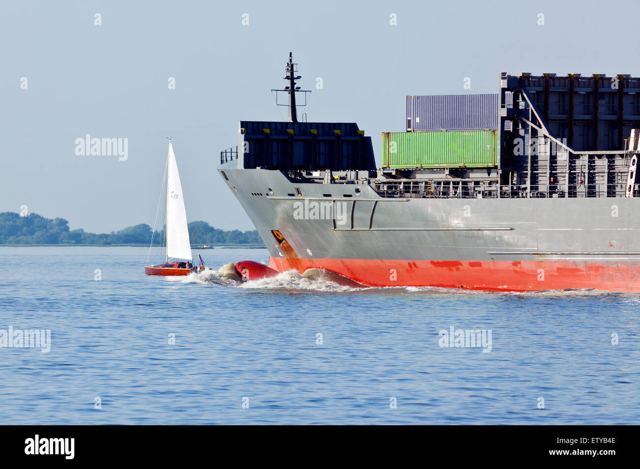 Ahnungslos Seemann Segelboot, große Feederschiff nähert sich von hinten Stockfoto