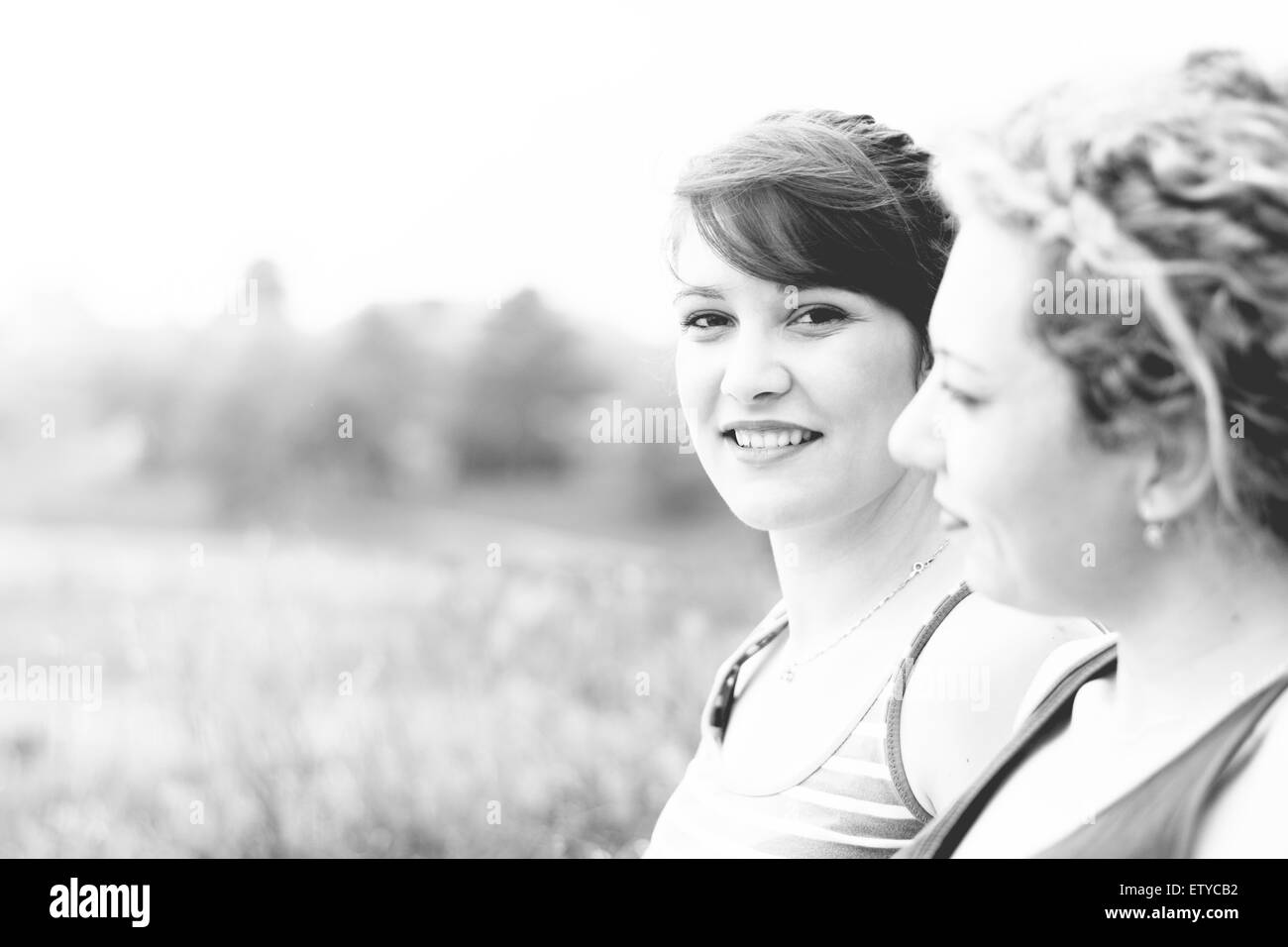 Closeup Portrait eine junge Brünette Mädchen sitzt neben ihre beste Freundin, Sommer genießen. Stockfoto