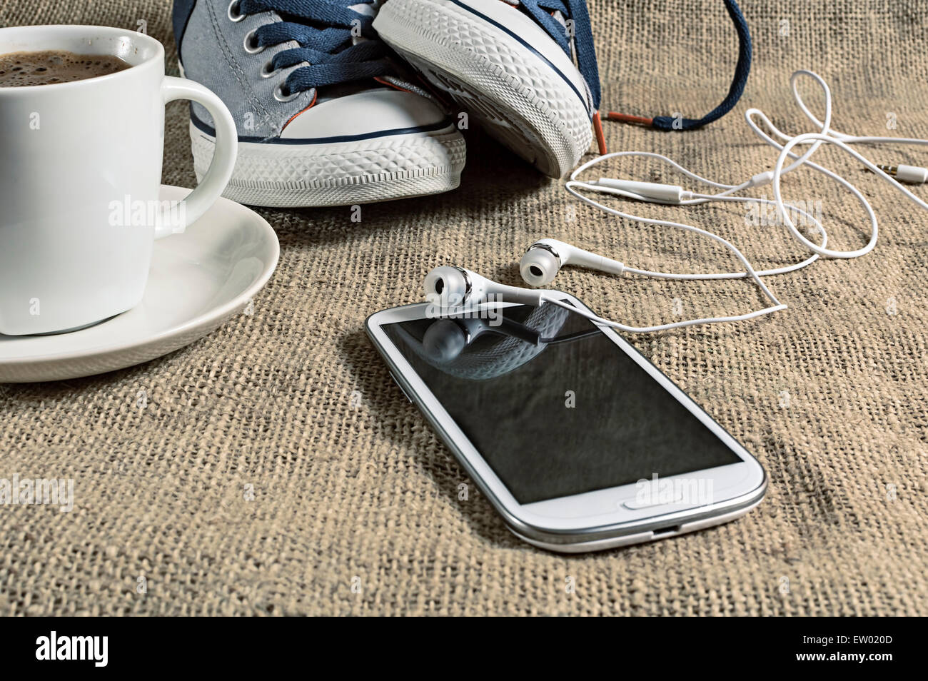 Smartphone mit Kaffee und Turnschuhe. Geringe Schärfentiefe. Stockfoto
