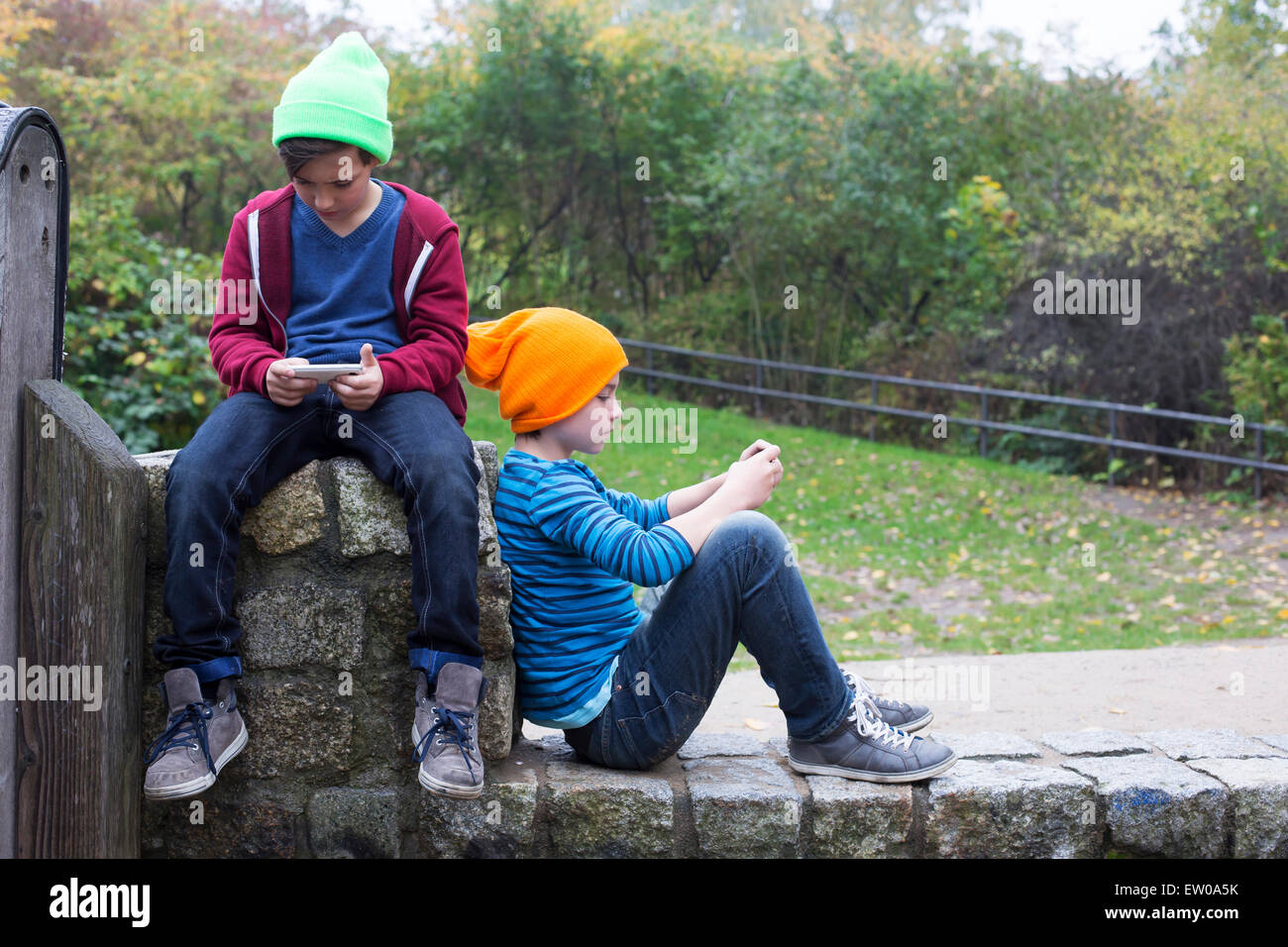 zwei jungen draußen zu sitzen und spielen mit ihren Handys Stockfoto