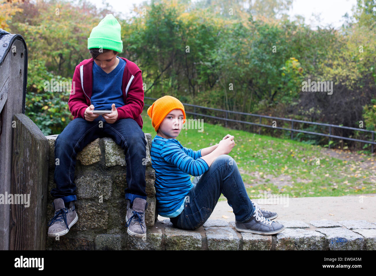 zwei jungen draußen zu sitzen und spielen mit ihren Handys Stockfoto