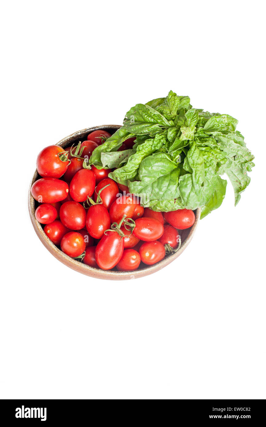 Teller mit rohen roten Tomaten und Basilikum frisch isoliert auf weißem Hintergrund vertikale Rahmen Stockfoto