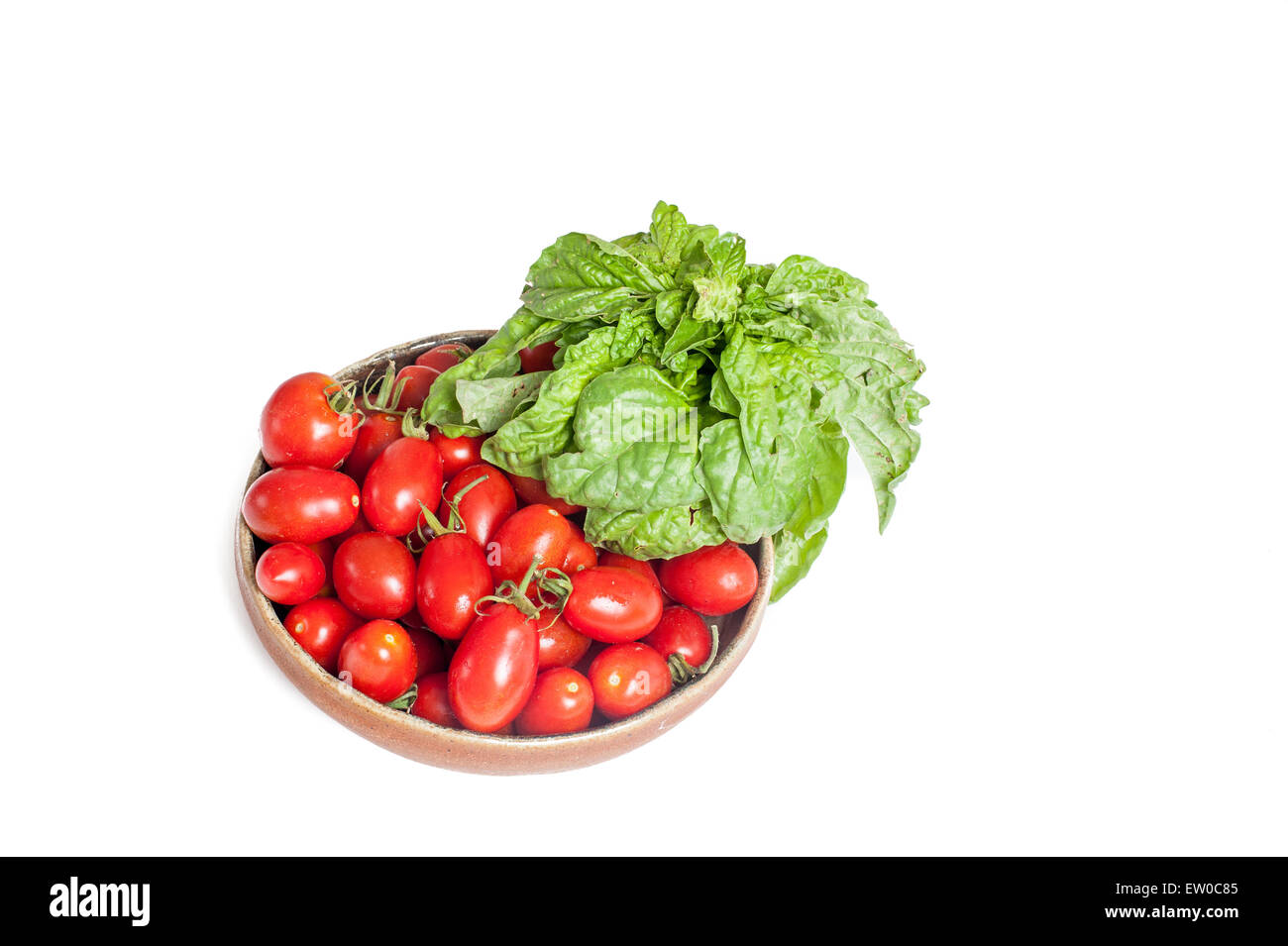 Teller mit rohen roten Tomaten und Basilikum frisch isoliert auf weißem Hintergrund Stockfoto