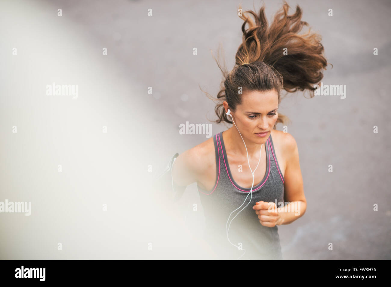 Ein Frau Jogger läuft, konzentriert und in der Zone als She plays Musik auf ihre Ohrhörer. Stockfoto