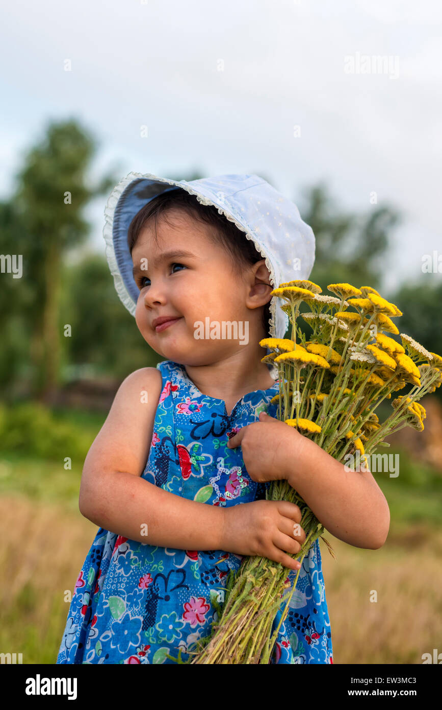 Niedliche kleine Mädchen hält einen Eimer mit Schafgarbe Blumen Stockfoto